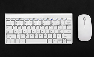 Computer mouse and keyboard on black background. Top view.