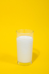 Glass of fresh milk on yellow background