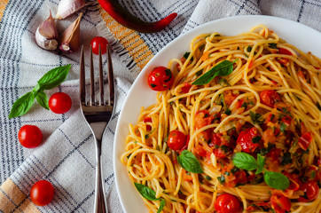 Italian spaghetti with tomato sauce. Cherry tomatoes and Basil on a white dish on a linen...