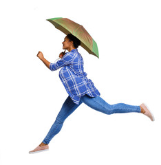 Side view of a woman balancing with an umbrella. girl jumps over a puddle.