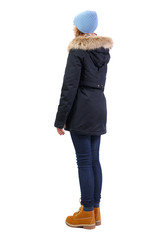 Side view woman in a black winter jacket with fur and blue hat.