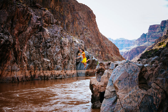 Two men leap into the Colorado River near Mile 237 of a rafting trip, Grand Canyon National Park, Arizona, USA