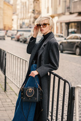  Outdoor fashion portrait of young elegant woman wearing classic gray coat, black turtleneck, wide...