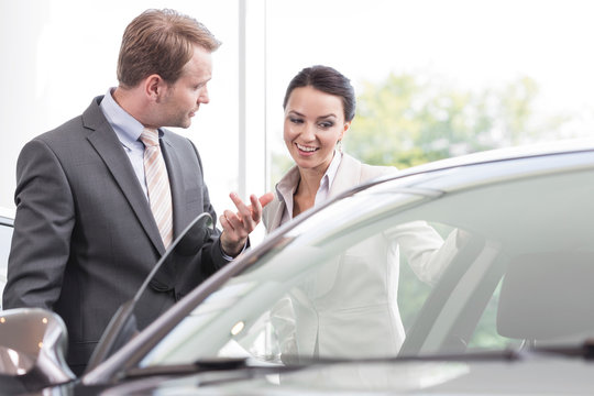 At the car dealer,Salesman showing new car to client