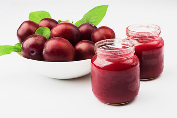 Violet fresh ripe plums and a glass with a puree from plums