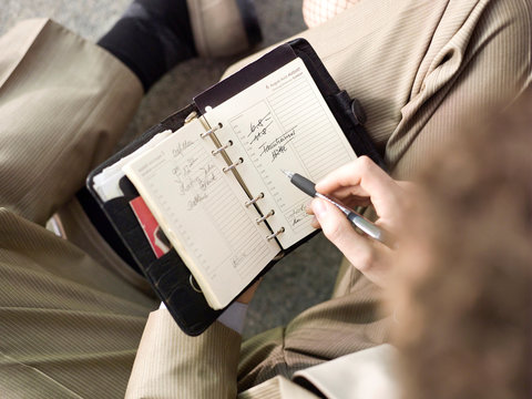 Businessman holding time planner, overhead view, close-up