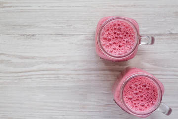 Raspberry smoothie in glass jar mugs, overhead view. Flat lay, from above, top view. Copy space.