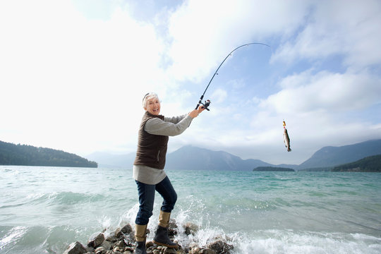 Germany, Bavaria, Walchsensee, Senior woman fishing in lake