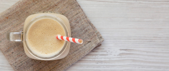 Peanut butter banana smoothie in a glass jar, overhead view. Top view, from above, flat lay. Copy space.