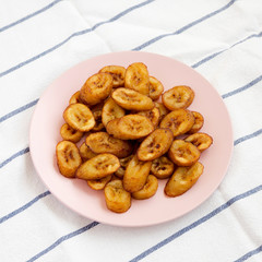 Homemade fried plantains on a pink plate, side view.