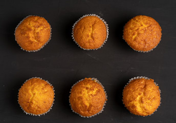 Appetizing muffins stand on a table top view. Traditional pastries on a dark background minimalism.