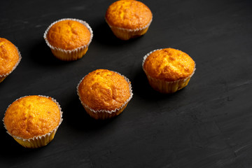 Appetizing muffins stand on a table top view. Traditional pastries on a dark background minimalism.