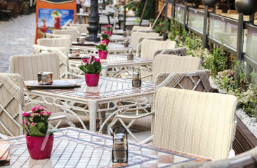 Cozy open summer cafe with pink flowers on the tables