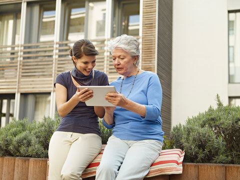 Germany, Cologne, Women looking digital tablet outside of nursing home