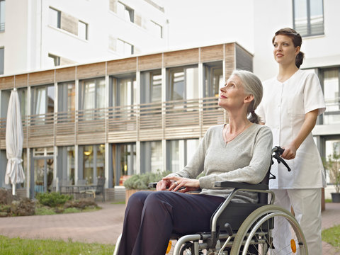 Germany, Cologne, Caretaker pushing senior women in wheelchair