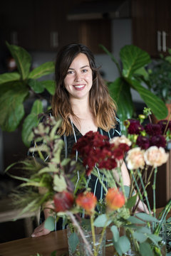 Smiling woman surrounded by houseplants in apartment