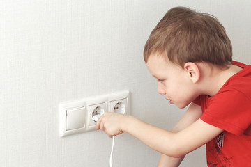 Toddler playing with electric plug at home. Dangerous situation for children with electricity