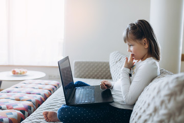 Girl sitting on sofa with laptop in scandinavian room interior, technology, new generation, scandinavian home concept