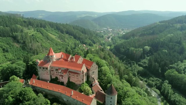 Aerial View of Fabulous Medieval Pernstejn Castle (hrad Pernstejn) in Mountain Forest in Czech Republic, Europe on Sunny Summer Day with Town and River at Background. 4K Bird's-eye view Pedestal Shot