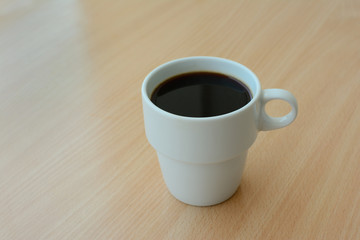 A cup of hot coffee on a wooden table, close-up