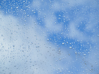 Raindrops on glass blue sky background.
