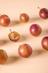 Pattern, texture of sliced half ripe sweet plum fruits with water drops on cream colored background, bright, angle view