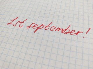 Handwritten inscription in felt-tip pen on the first of september on squared paper. Preparation for school, the beginning of the school year, September 1, a sheet in a cage