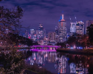 Fototapeta na wymiar Melbourne Skyline at night with magenta lit bridge in foreground