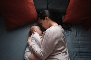 Mother with baby girl sleeping on bed