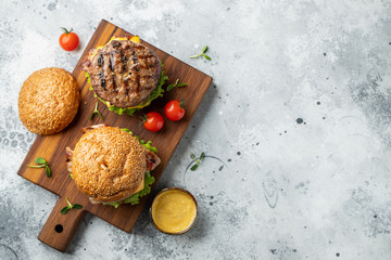 Tasty grilled home made burger with beef, tomato, cheese, bacon and lettuce on a light stone background with copy space. Top view. fast food and junk food concept. Flat lay - obrazy, fototapety, plakaty