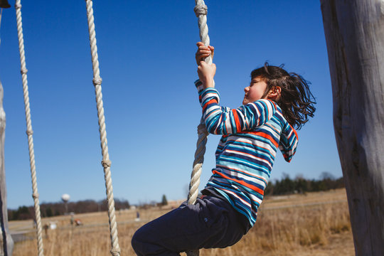A child works hard to pull himself up a rope on obstacle course