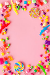 Assorted sweets and lollipop frame on pink background top view space for text