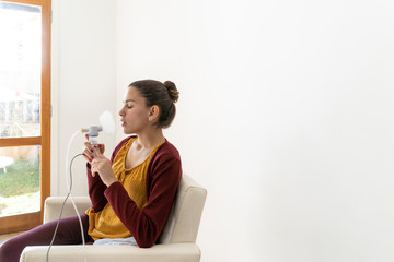 Girl sneezing while inhalation nebulizer in hospital, holding a mask nebuliser inhaling asthma and...