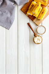 Fried corn on board with salt and butter on white wooden background top view mockup
