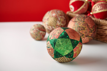 Patchwork puzzle balls and christmas decorations in basket on white and red background
