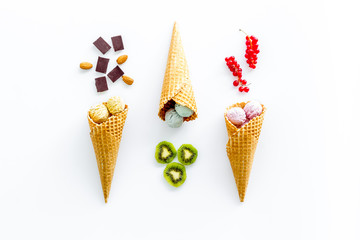Gelato in waffle cone with kiwi, hazelnut, chocolate and wineberry on white backgroung top view