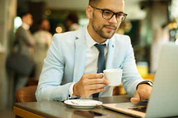 Young businessman uses a laptop in a cafe