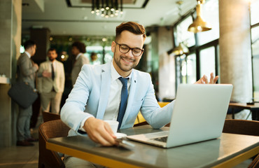 Fototapeta premium Young businessman uses a laptop in a cafe