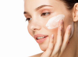 young woman applying moisturizing cream on her face. Skin care concept