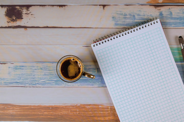 Notepad with pen and espresso coffee on table.