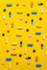 Various types of pills on yellow background