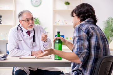 Obraz premium Young male alcoholic visiting old doctor