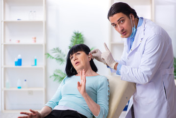 Old woman visiting young doctor laryngologist