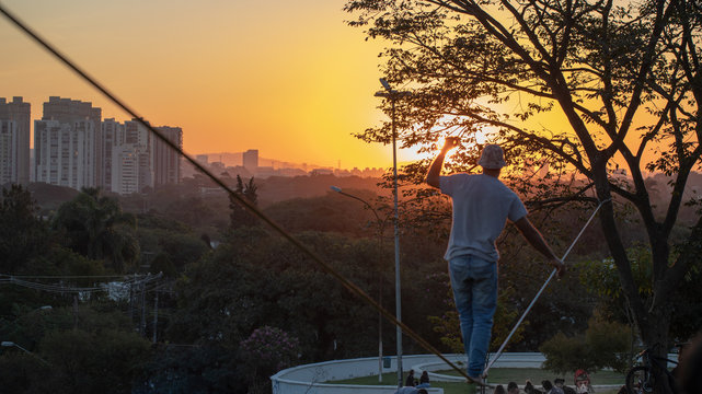 homem praticando esporte slackline corda arvore por do sol