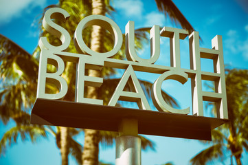 Scenic sunlit view of the entrance to South Beach sign with a tropical palm tree in Miami, Florida, USA