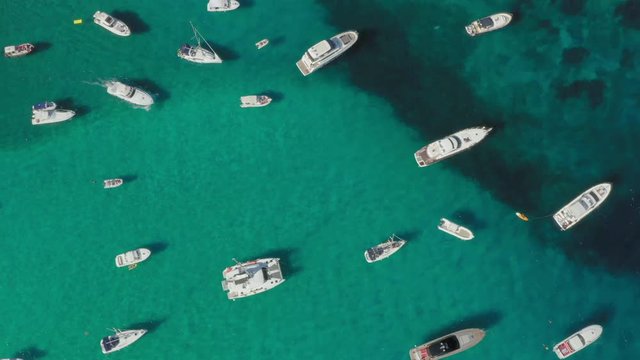 View from above, stunning aerial view of the beautiful Cala Di Volpe bay full of boats and luxury yachts. A turquoise sea bathes the green and rocky coasts. Emerald Coast, Sardinia, Italy.