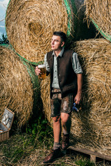 Mann in Bayerischer Tracht vor einem Strohballen 