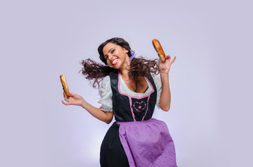 Cute young woman in Oktoberfest dress holding two Bavarian pretzels  