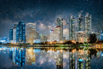 Obraz premium Beautiful cityscape in business district at night with milky way background reflected in the river, Bangkok city skyline