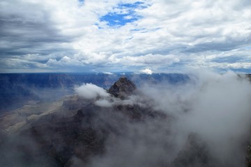 Fototapeta na wymiar Clouds and Fog Swirl Around Craggy Outcropping at North Rim of Grand Canyon
